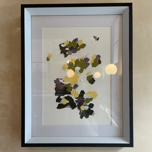 Framed artwork with abstract floral design on a beige wall green purple