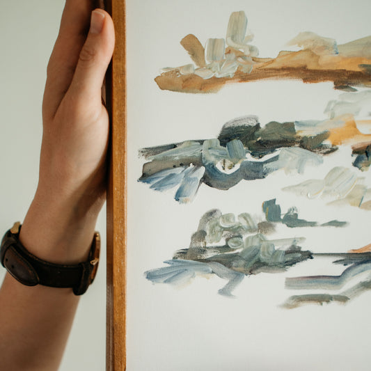Person holding a framed acrylic abstract landscape painting
